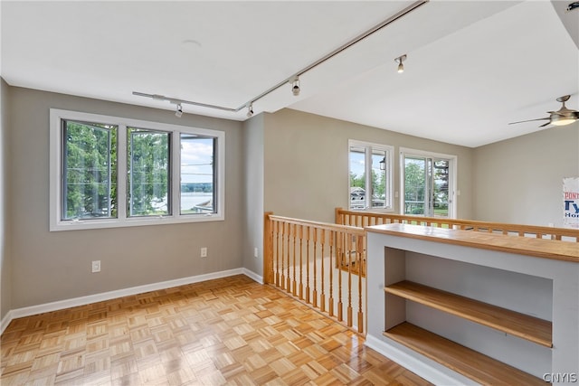 unfurnished room featuring ceiling fan, a healthy amount of sunlight, rail lighting, and light parquet floors