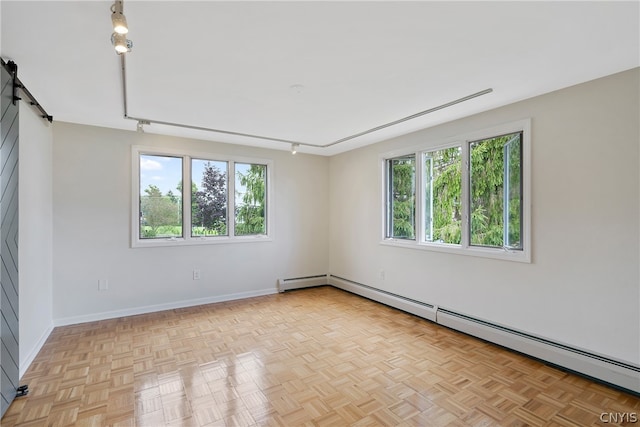 unfurnished room featuring a barn door, baseboard heating, and light parquet floors