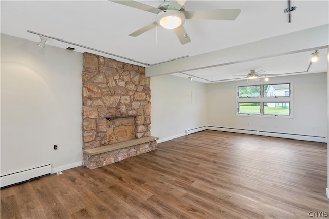 unfurnished living room with hardwood / wood-style floors, rail lighting, a fireplace, ceiling fan, and baseboard heating