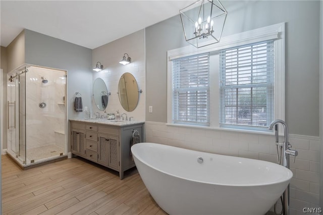 bathroom with vanity, plus walk in shower, wood-type flooring, and tile walls