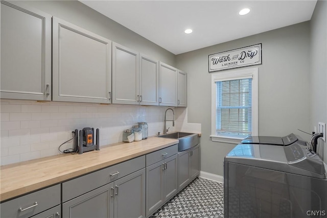 clothes washing area with cabinets, sink, and washing machine and dryer