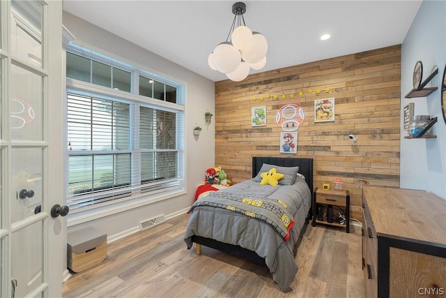 bedroom featuring light hardwood / wood-style floors and wood walls