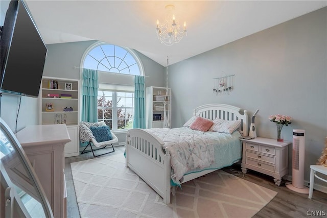 bedroom with light hardwood / wood-style flooring, a notable chandelier, and vaulted ceiling