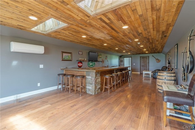 interior space featuring hardwood / wood-style flooring, a breakfast bar area, wooden ceiling, and an AC wall unit