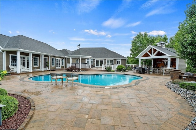 view of swimming pool featuring an outbuilding, an outdoor bar, and a patio