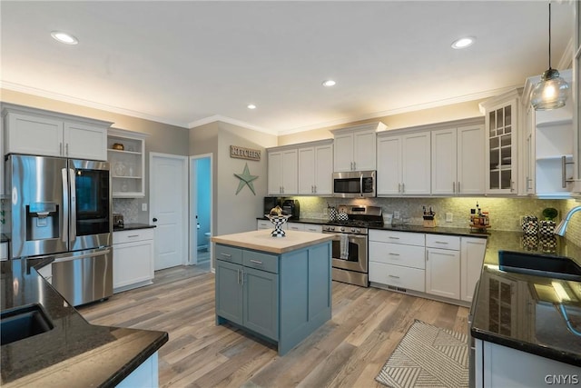 kitchen with appliances with stainless steel finishes, decorative light fixtures, sink, white cabinets, and a center island