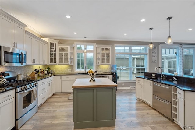 kitchen featuring pendant lighting, sink, stainless steel appliances, and an island with sink