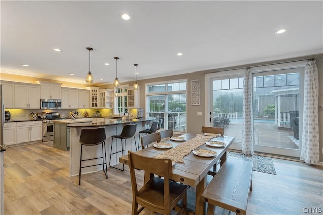 dining space featuring ornamental molding, sink, and light wood-type flooring