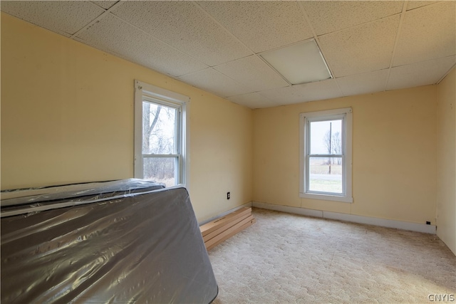 unfurnished bedroom with light carpet and a paneled ceiling