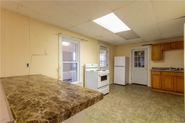 kitchen with sink, white appliances, light tile patterned floors, and a paneled ceiling