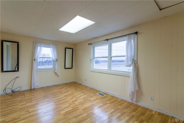 unfurnished room with a paneled ceiling and light hardwood / wood-style flooring