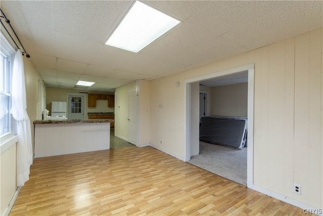 unfurnished living room with light carpet and a paneled ceiling