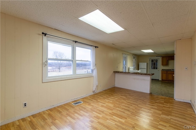 unfurnished living room with light hardwood / wood-style flooring and a paneled ceiling