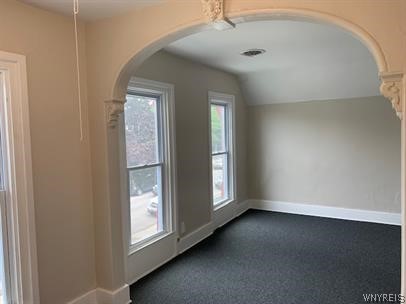 bonus room with dark carpet and vaulted ceiling