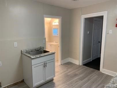 kitchen with wood-type flooring, sink, and white cabinets