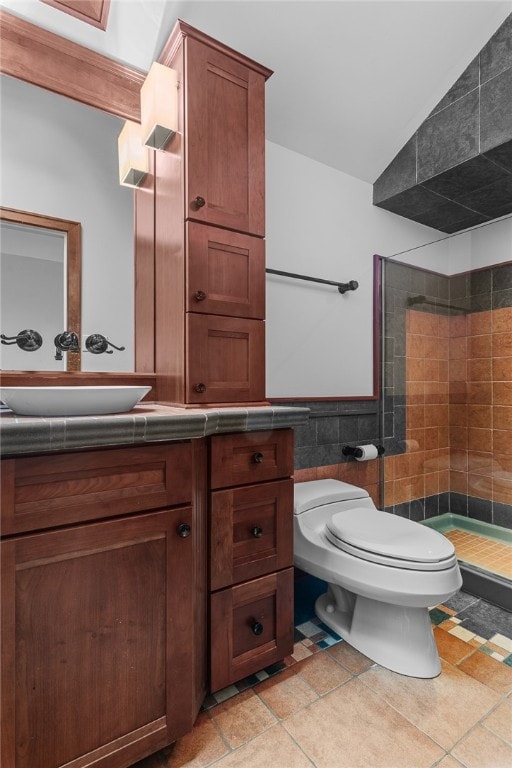 bathroom with tile walls, vanity, a tile shower, lofted ceiling, and toilet