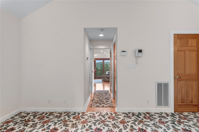 hallway featuring lofted ceiling and hardwood / wood-style flooring