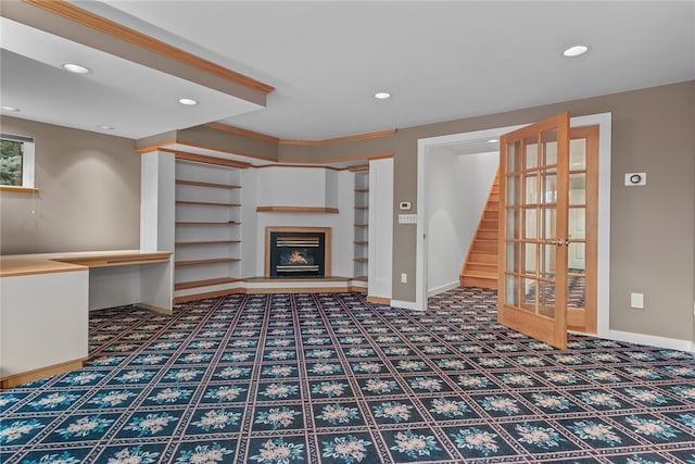 unfurnished living room featuring built in shelves, carpet, and crown molding