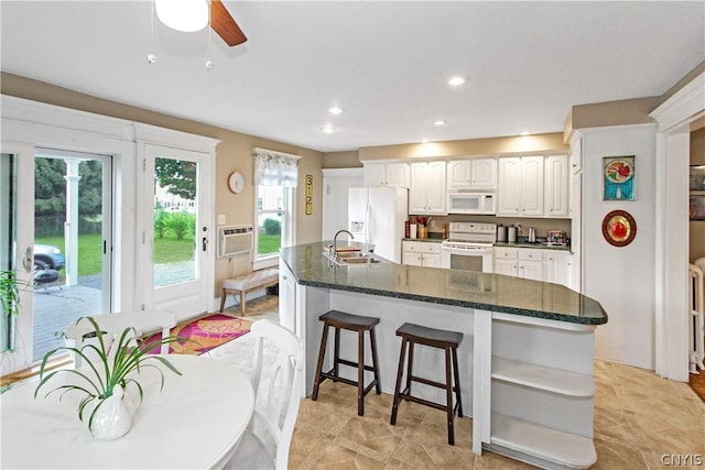 kitchen featuring white cabinetry, sink, a wall mounted AC, dark stone counters, and white appliances