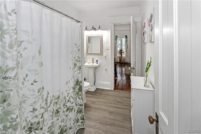 bathroom featuring wood-type flooring, sink, curtained shower, and toilet