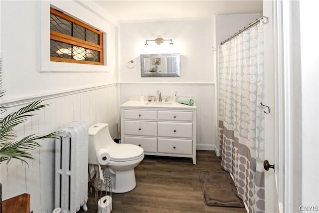 bathroom with hardwood / wood-style flooring, radiator heating unit, a shower with shower curtain, vanity, and toilet