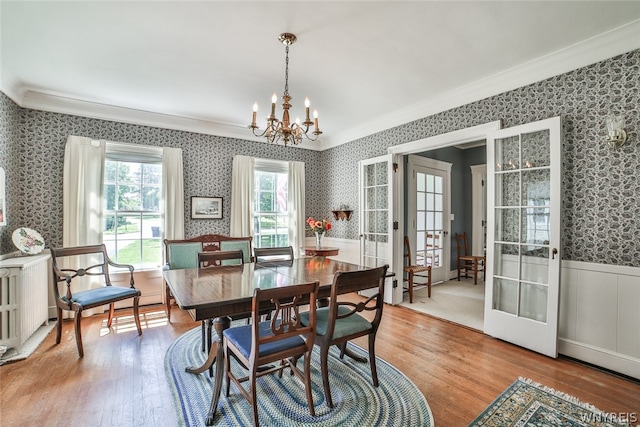 dining area featuring a chandelier, french doors, crown molding, and light hardwood / wood-style floors