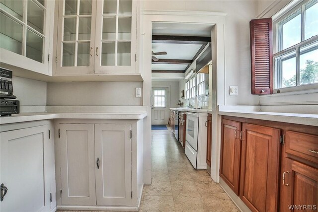 kitchen with plenty of natural light, stove, beamed ceiling, and white cabinetry