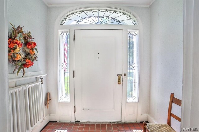 tiled foyer with ornamental molding and radiator heating unit