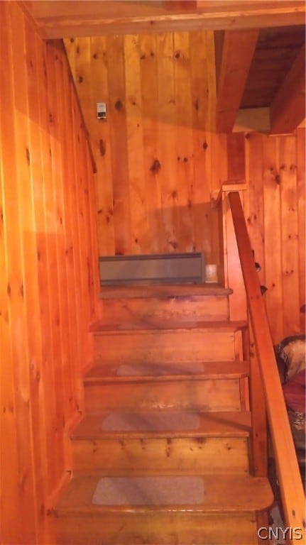 stairway featuring wooden walls