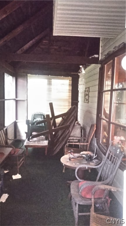 living room with lofted ceiling, wood walls, and carpet flooring