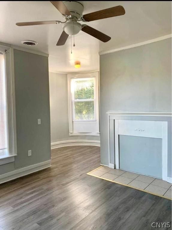 unfurnished living room featuring hardwood / wood-style flooring, ornamental molding, and plenty of natural light