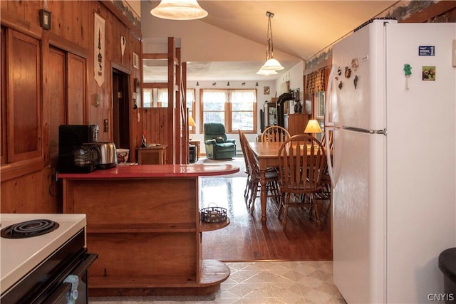 kitchen with stove, light hardwood / wood-style flooring, vaulted ceiling, decorative light fixtures, and white fridge