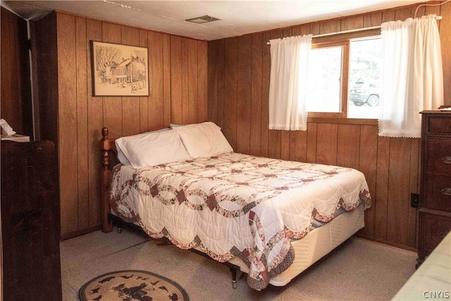 bedroom with light colored carpet and wooden walls