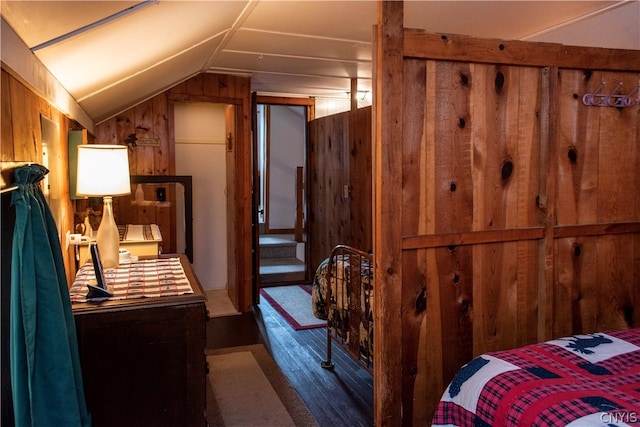 bedroom featuring lofted ceiling and wood walls