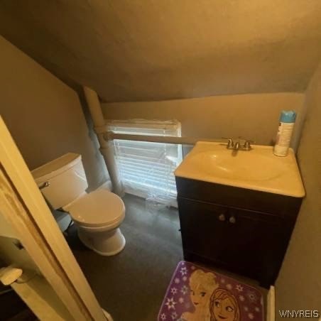 bathroom with vaulted ceiling, toilet, and vanity