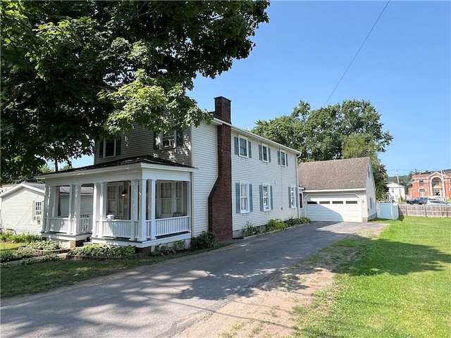 colonial-style house with a front lawn, a porch, a chimney, a garage, and driveway