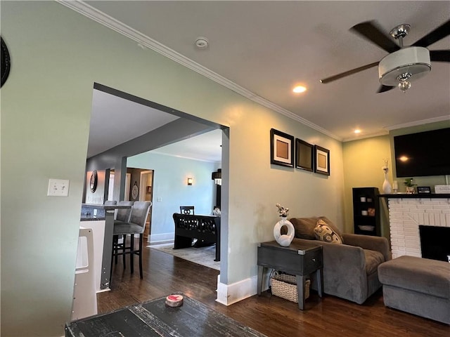 living area with wood finished floors, a fireplace, crown molding, baseboards, and ceiling fan