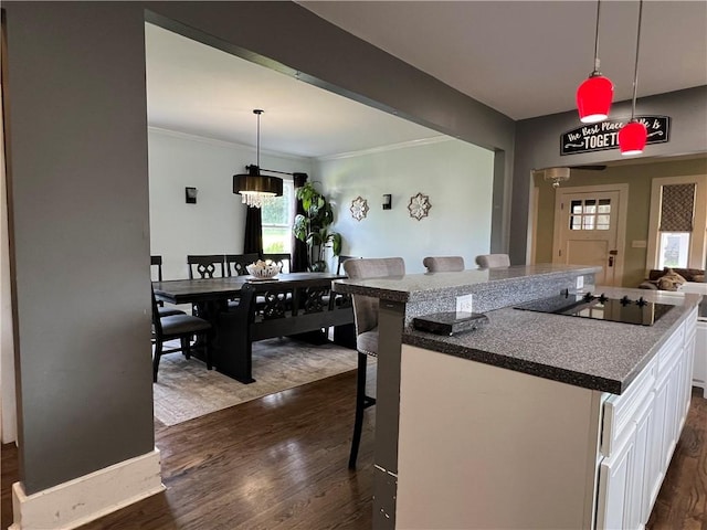 kitchen featuring white cabinetry, decorative light fixtures, dark wood-style floors, and a breakfast bar