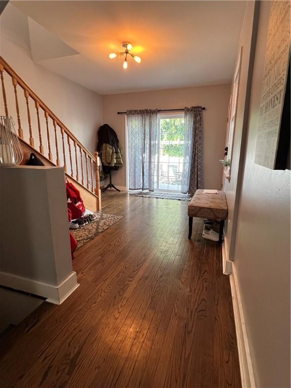 unfurnished living room with stairway, wood finished floors, and baseboards