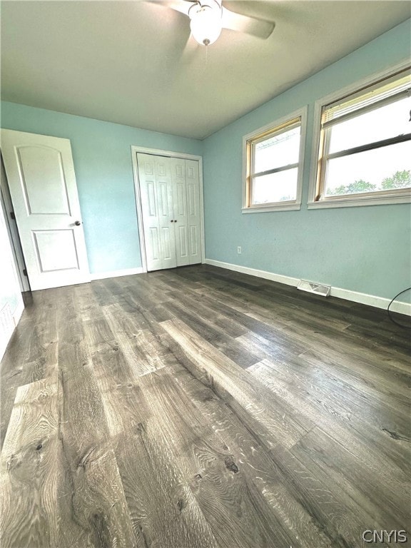 unfurnished bedroom featuring ceiling fan, dark hardwood / wood-style flooring, and a closet