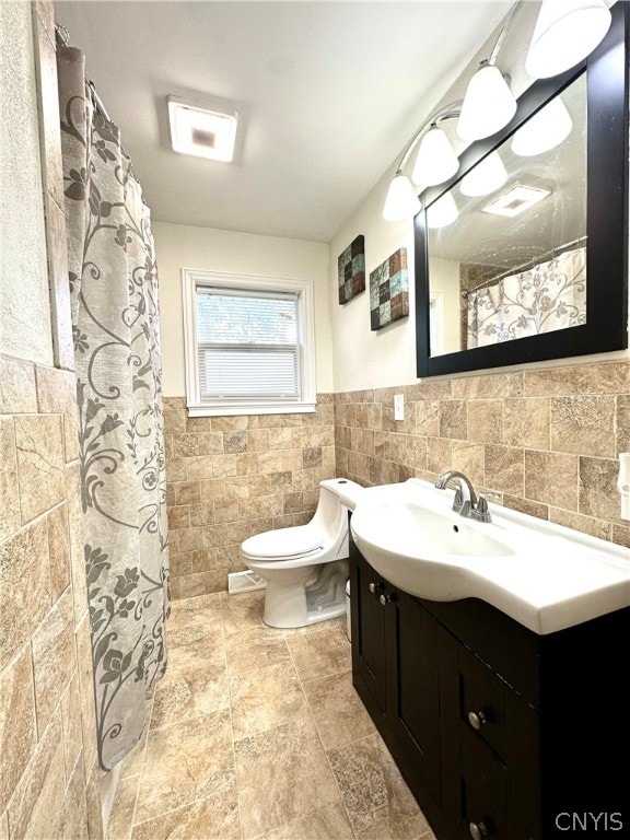 bathroom with vanity, tile walls, and toilet