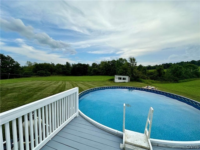 view of pool with a wooden deck, a yard, and a storage unit