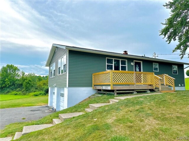 rear view of property featuring a wooden deck, a yard, and a garage