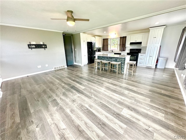 unfurnished living room featuring ceiling fan, sink, light wood-type flooring, and ornamental molding