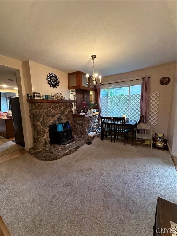 dining area with carpet floors, a chandelier, and a stone fireplace