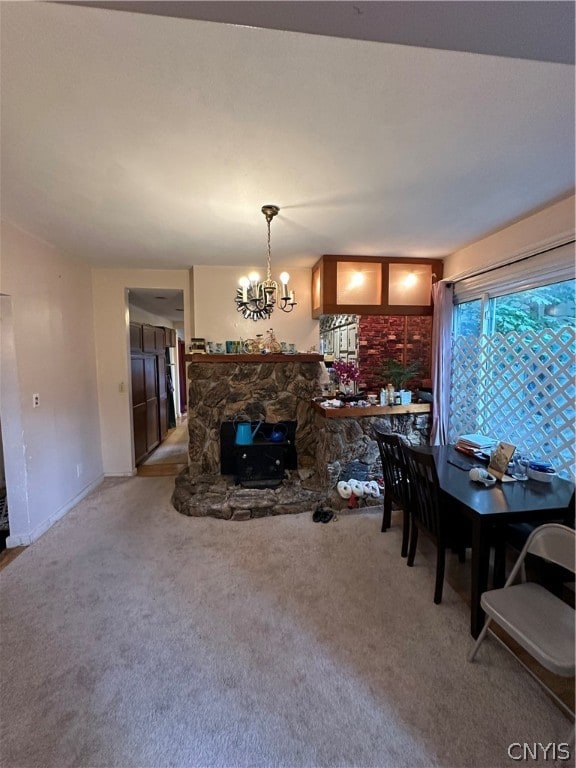 carpeted dining room featuring a stone fireplace and a chandelier