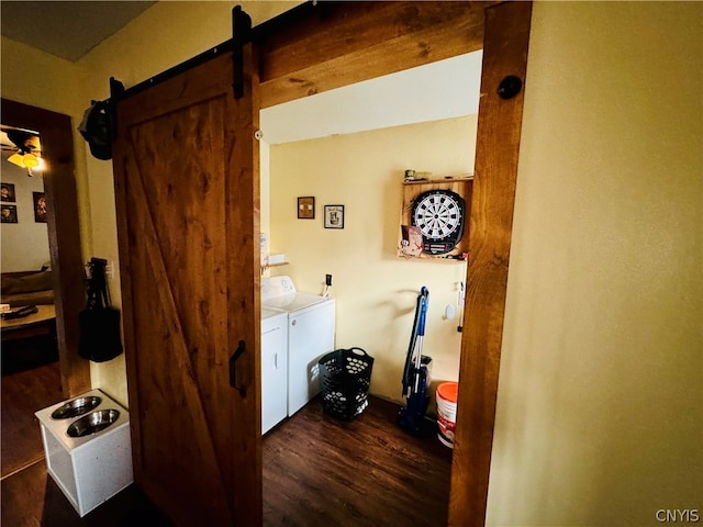 laundry area featuring a barn door, washing machine and dryer, ceiling fan, and dark hardwood / wood-style floors