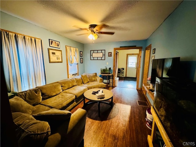 living room with a textured ceiling, ceiling fan, and wood-type flooring