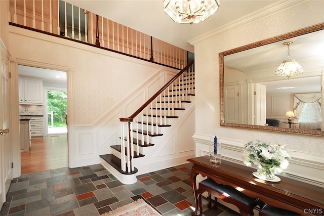 stairway with dark wood-type flooring, a chandelier, and crown molding