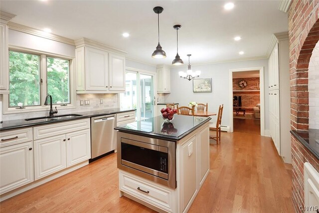 kitchen with a wealth of natural light, backsplash, stainless steel appliances, light hardwood / wood-style floors, and sink